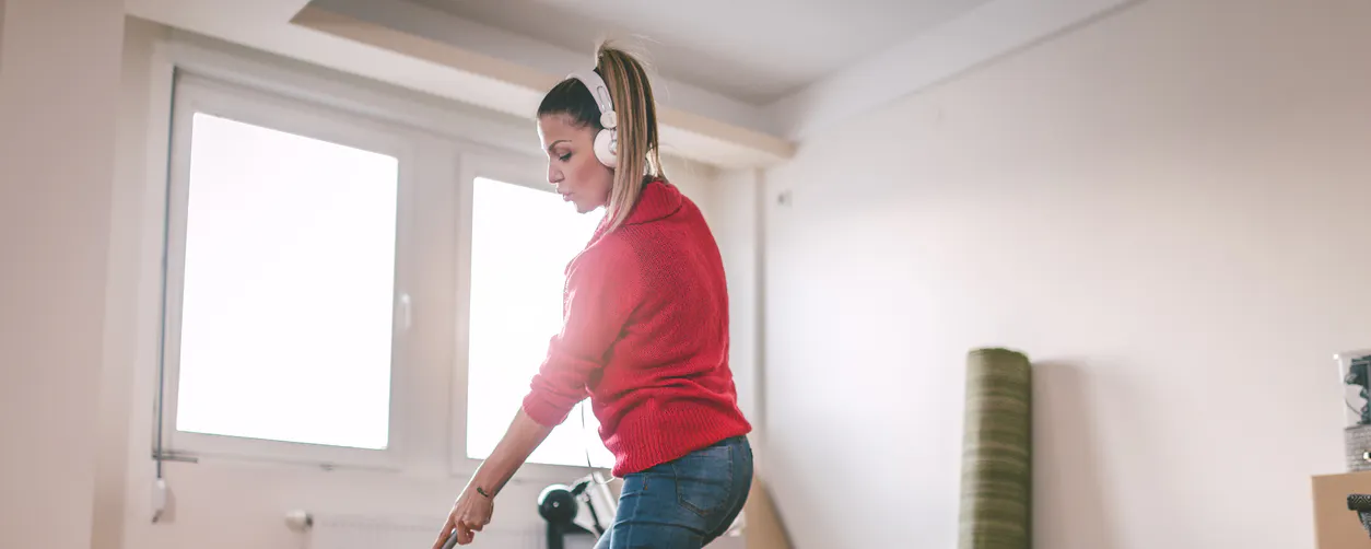 Femme avec casque audio nettoyant un parquet avec une serpillière