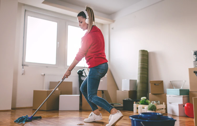 Femme avec casque audio nettoyant un parquet avec une serpillière