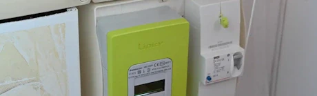 Main appuyant sur le bouton d'un compteur électrique Linky vert
