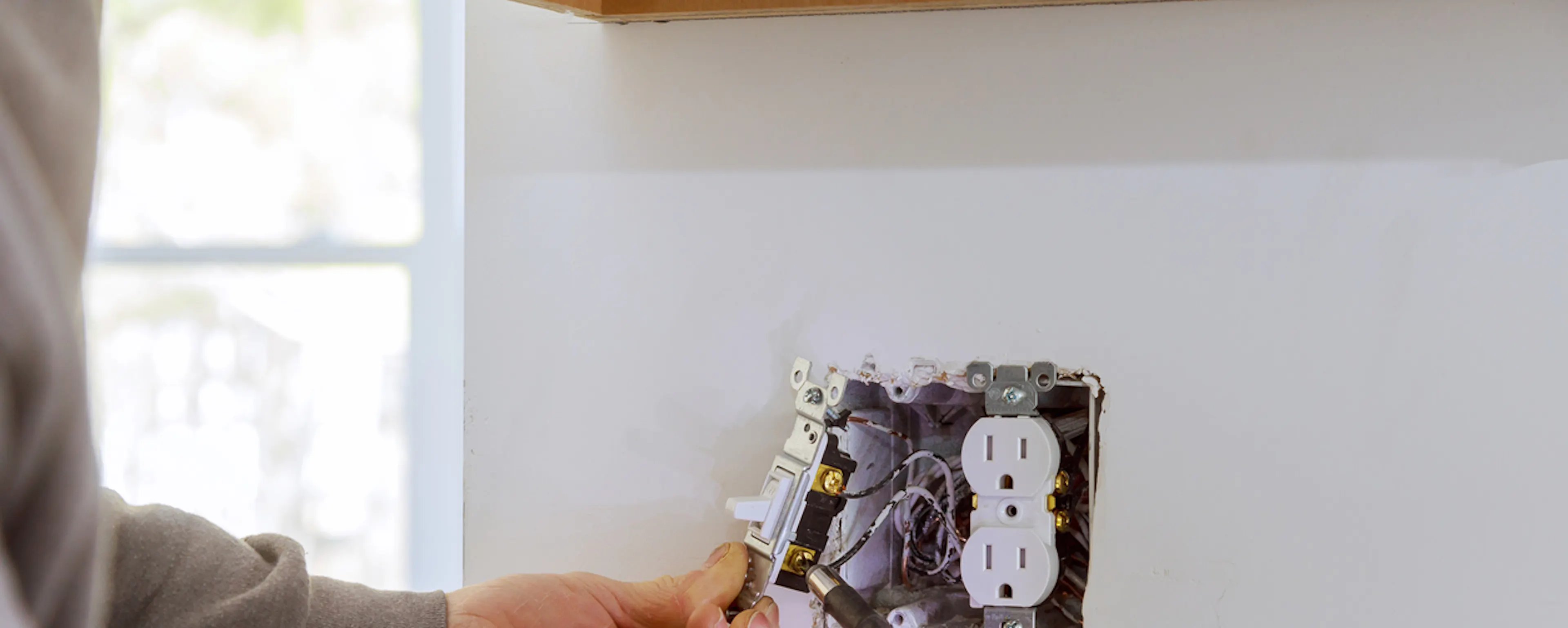 Électricien installant une prise murale avec une perceuse jaune