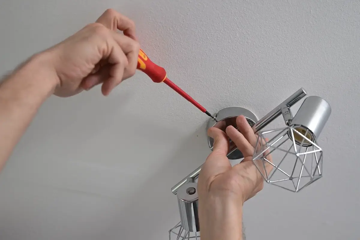 Mains fixant une applique murale décorative au plafond