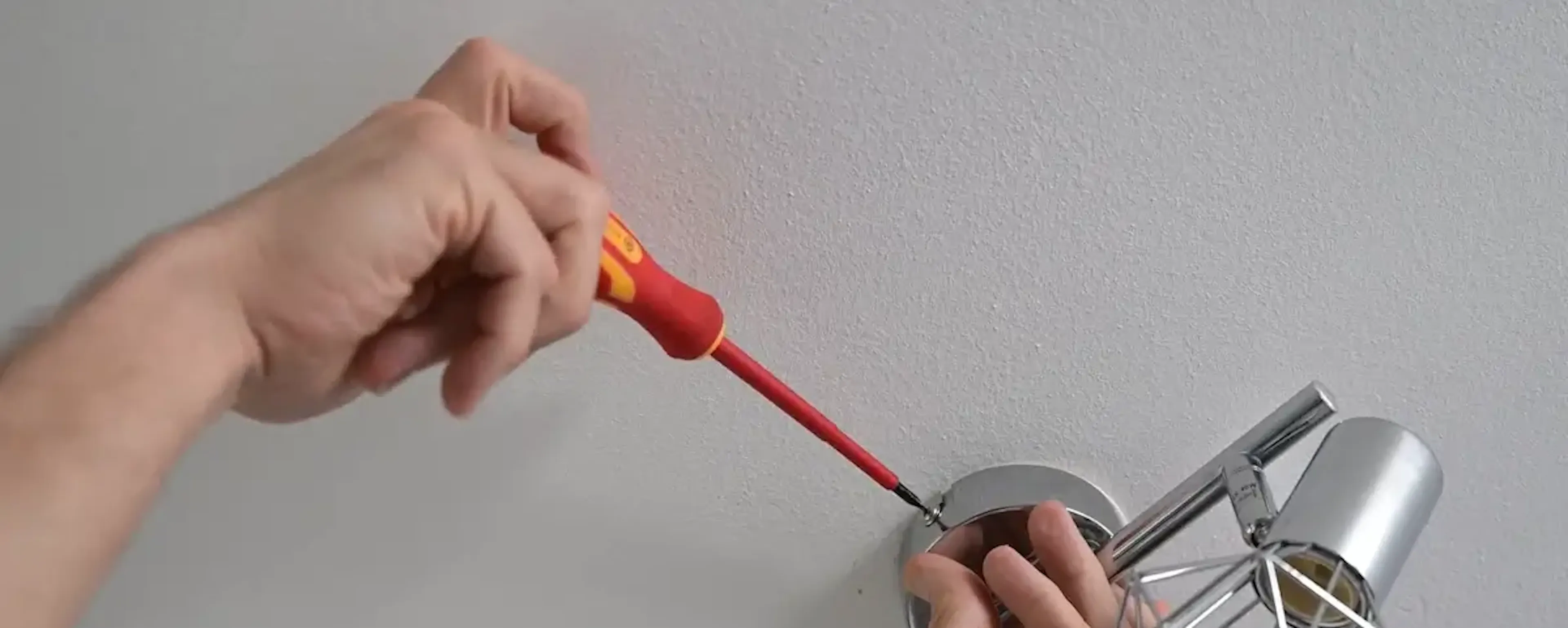 Mains fixant une applique murale décorative au plafond
