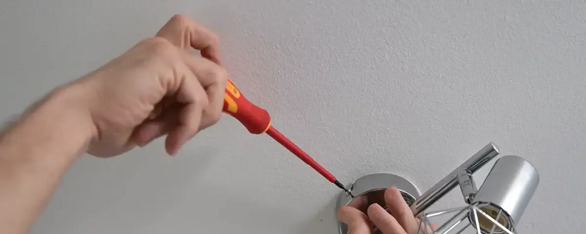 Mains fixant une applique murale décorative au plafond