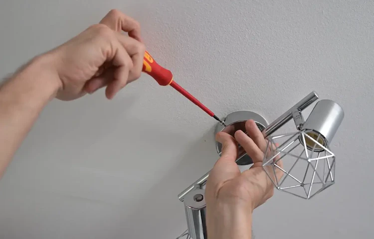 Mains fixant une applique murale décorative au plafond