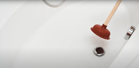 Ventouse posée près d'un siphon de baignoire blanche