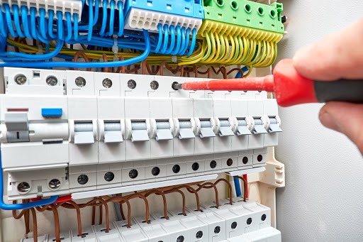 Électricien travaillant sur un tableau électrique avec des câbles colorés
