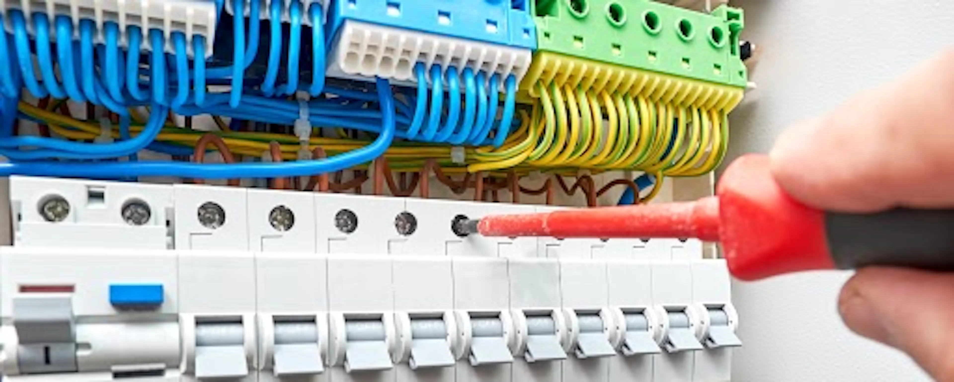 Électricien travaillant sur un tableau électrique avec des câbles colorés