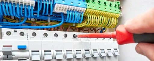 Électricien travaillant sur un tableau électrique avec des câbles colorés