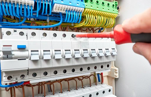 Électricien travaillant sur un tableau électrique avec des câbles colorés