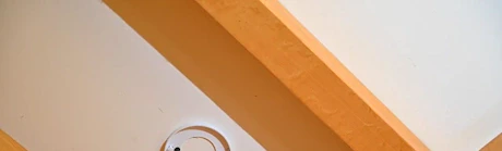Mains vissant un détecteur de fumée au plafond à l'aide d'un tournevis