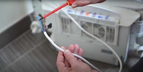 Mains raccordant un tuyau flexible blanc avec un tournevis rouge
