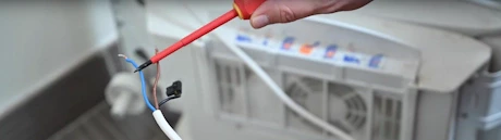 Mains raccordant un tuyau flexible blanc avec un tournevis rouge