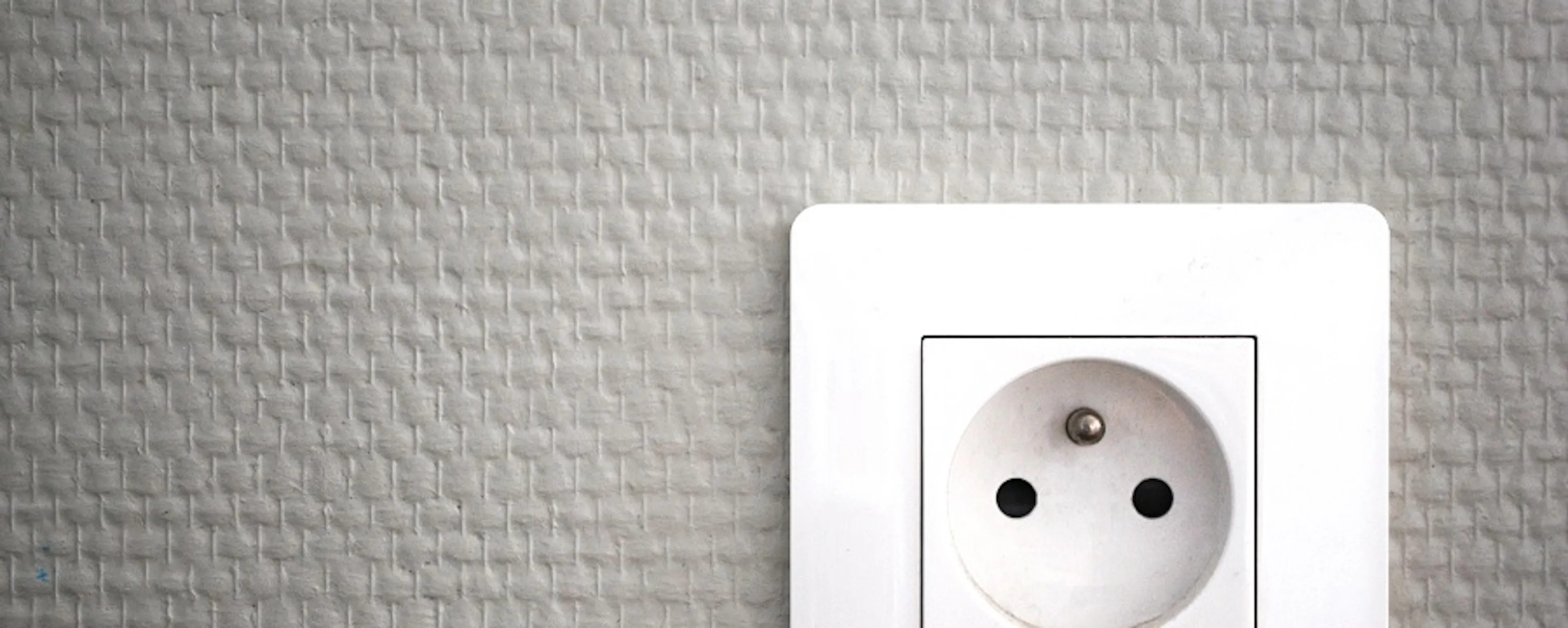 Prise électrique murale blanche sur fond gris texturé