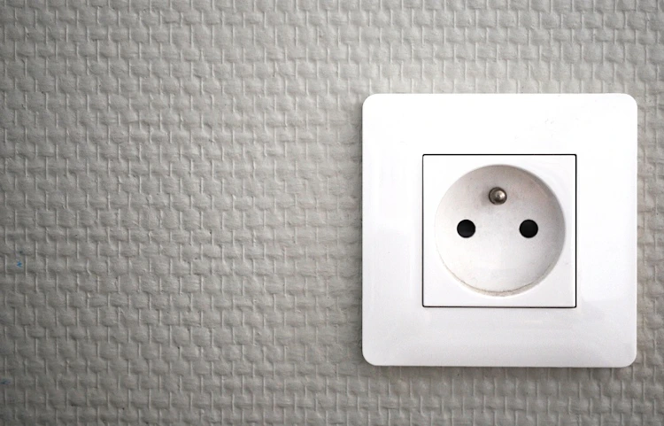 Prise électrique murale blanche sur fond gris texturé