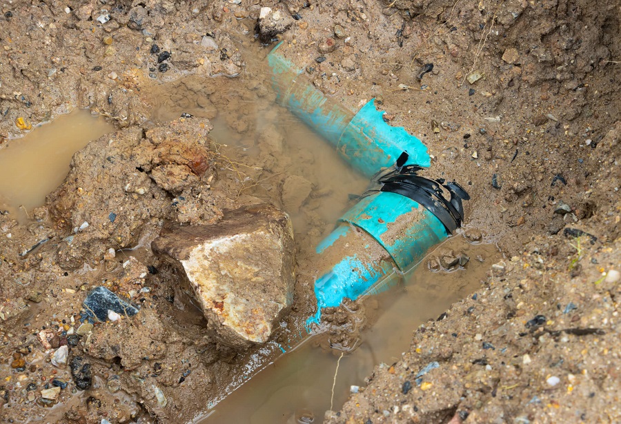 Canalisations bleues endommagées enterrées dans la terre boueuse