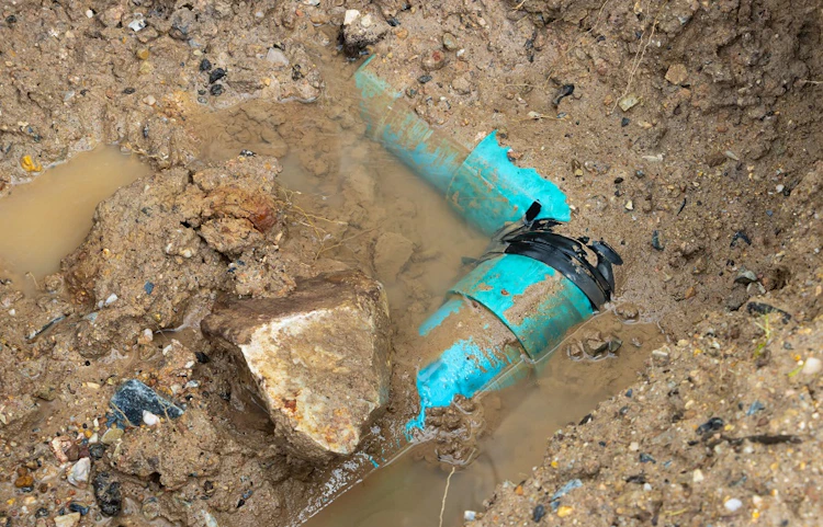 Canalisations bleues endommagées enterrées dans la terre boueuse