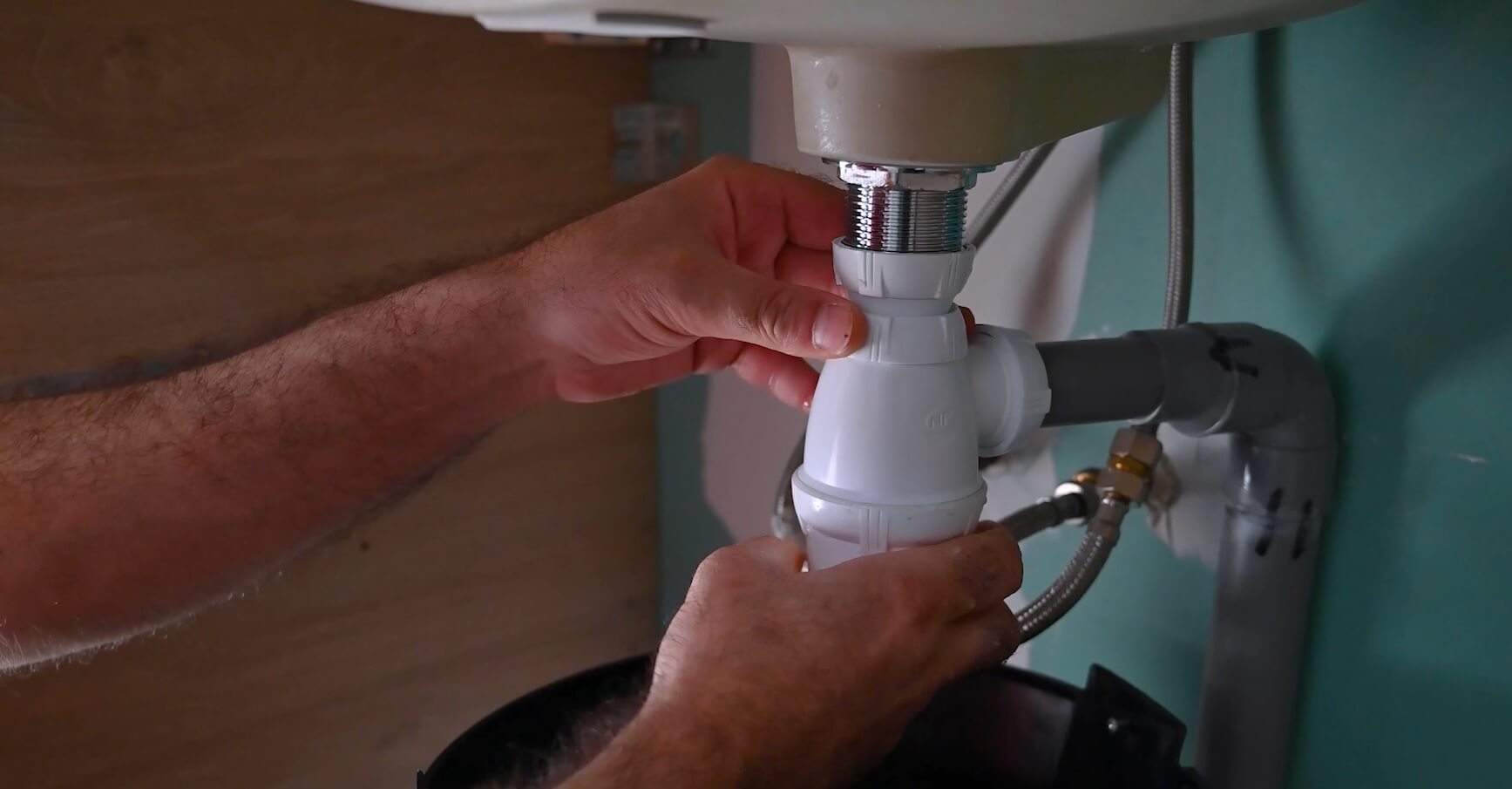 Mains resserrant le siphon en PVC sous un lavabo