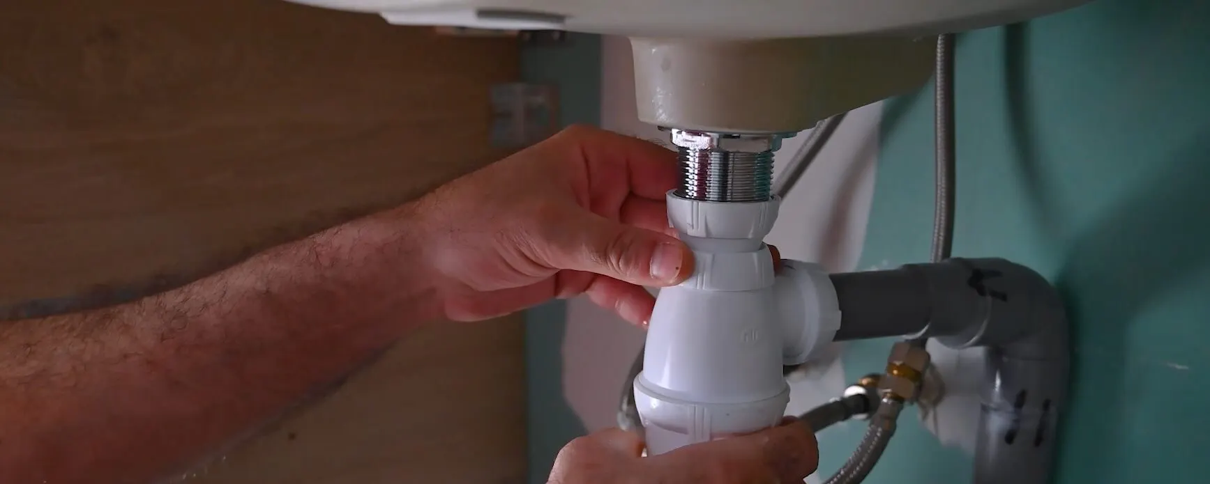 Mains resserrant le siphon en PVC sous un lavabo
