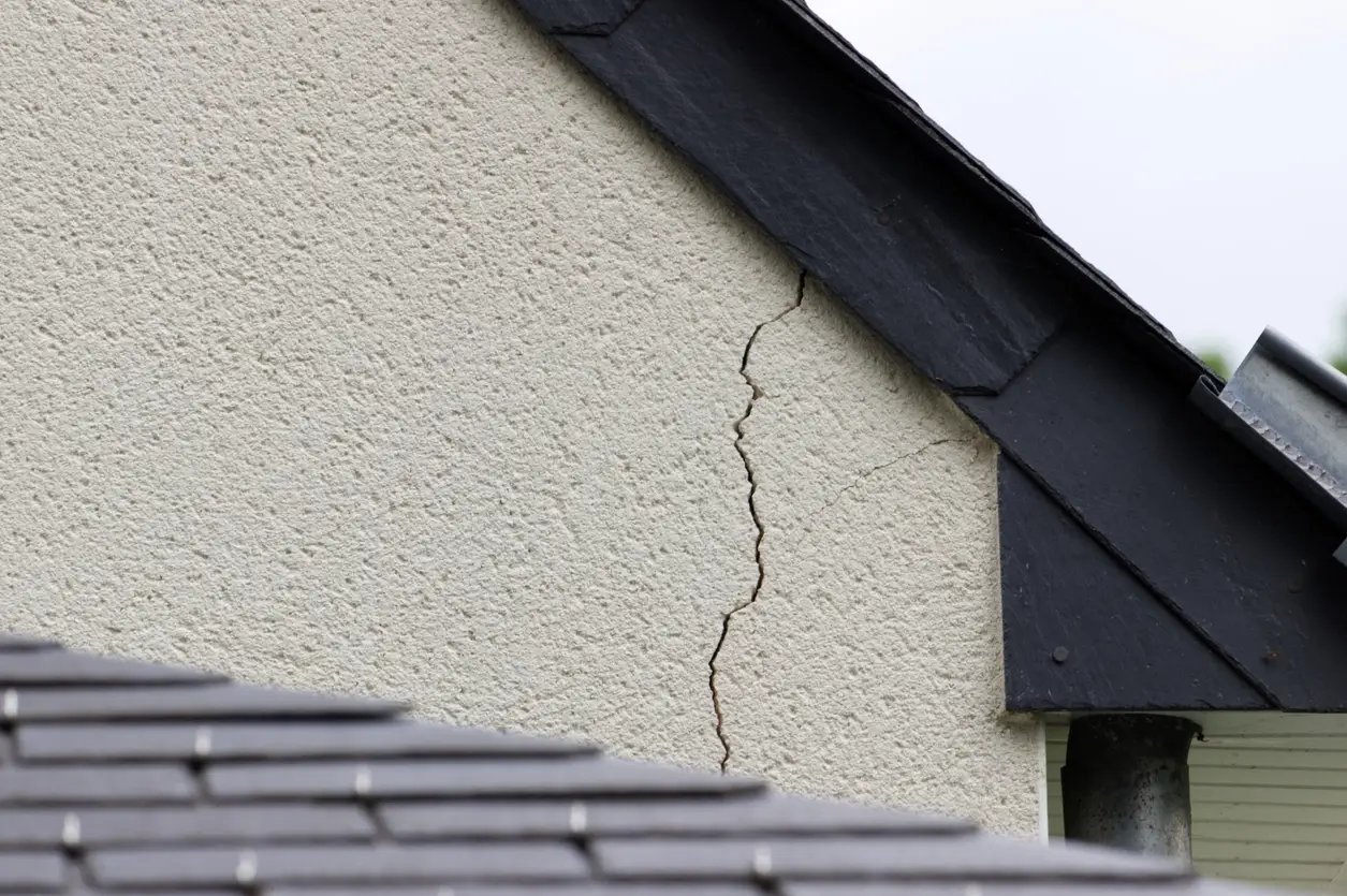 Fissure verticale sur le mur extérieur d'une maison près du toit