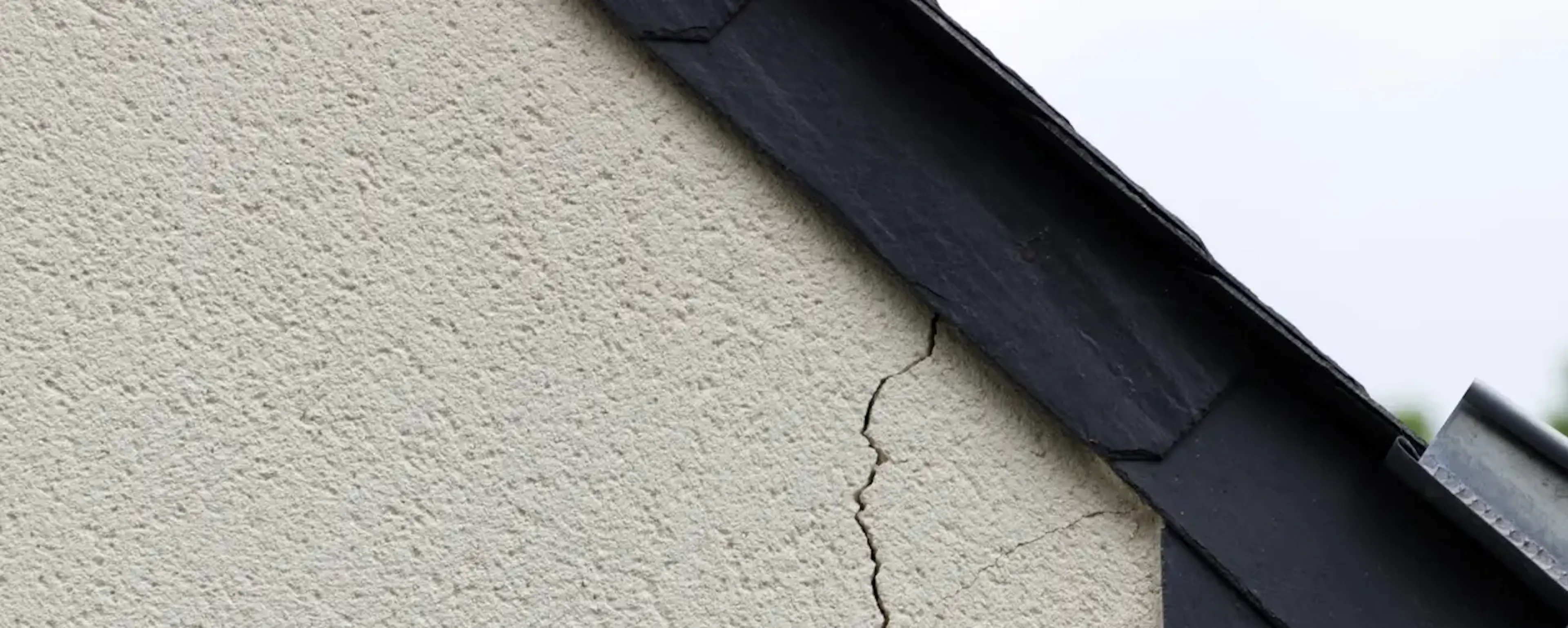 Fissure verticale sur le mur extérieur d'une maison près du toit