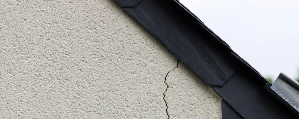 Fissure verticale sur le mur extérieur d'une maison près du toit