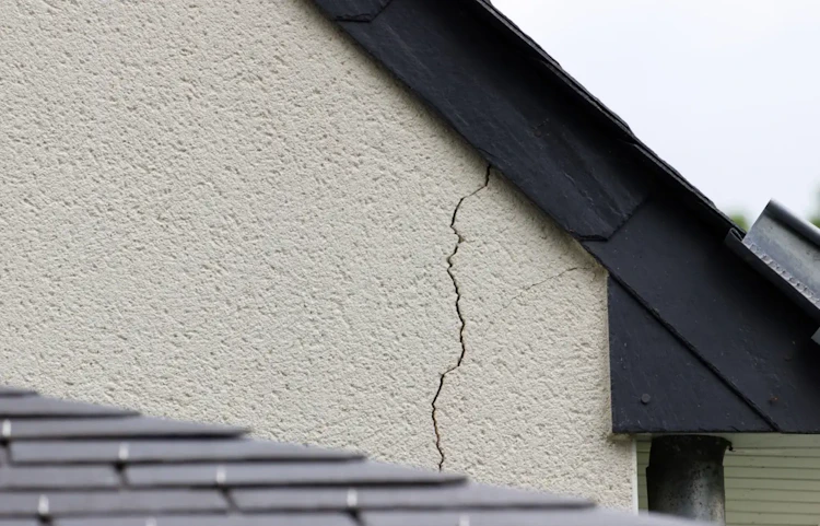 Fissure verticale sur le mur extérieur d'une maison près du toit