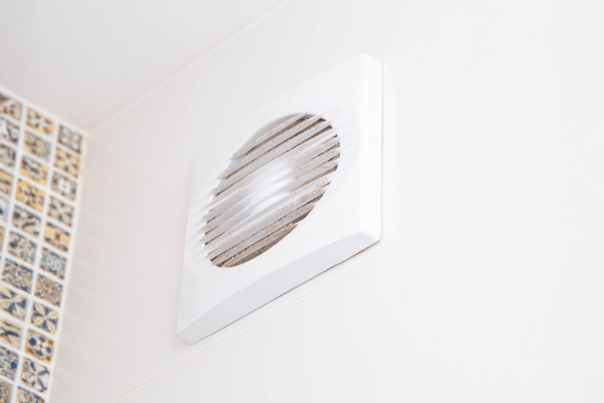 Bouche d'aération blanche fixée au mur d'une pièce