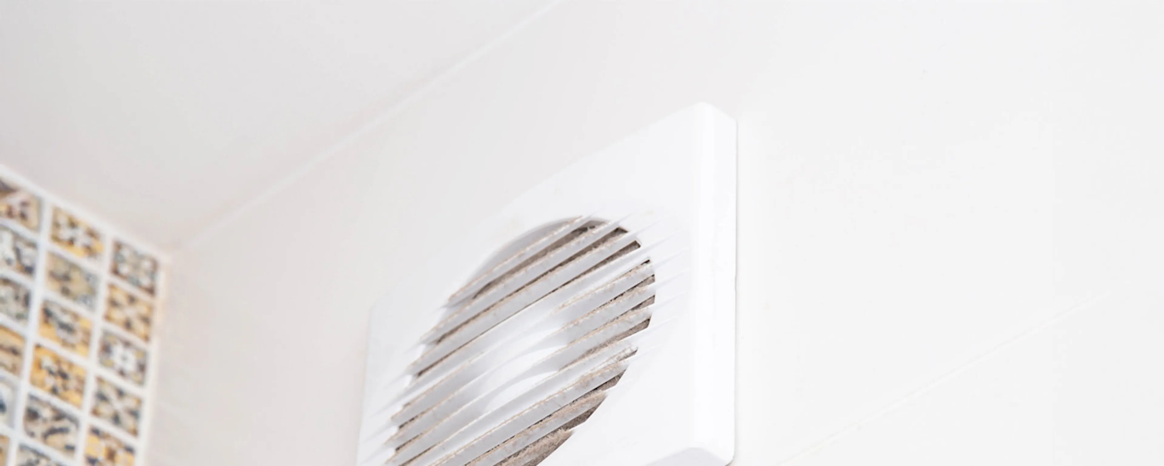 Bouche d'aération blanche fixée au mur d'une pièce