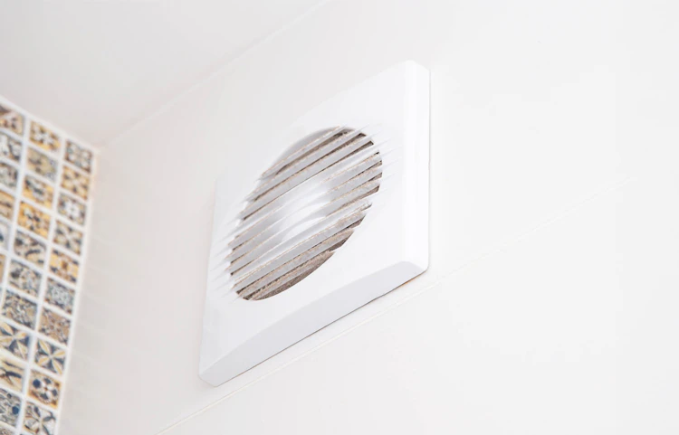 Bouche d'aération blanche fixée au mur d'une pièce