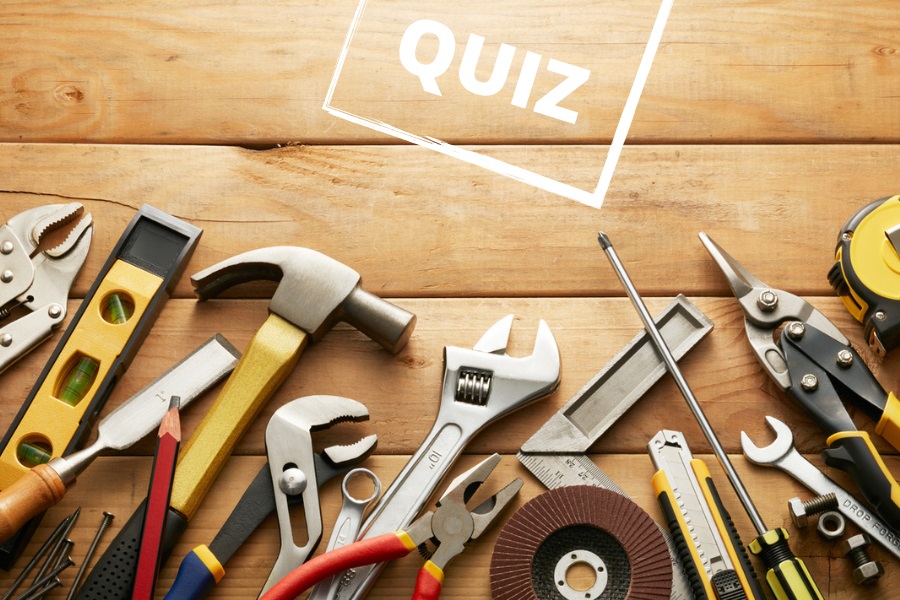 Assortiment d'outils de bricolage sur fond en bois avec le mot QUIZ