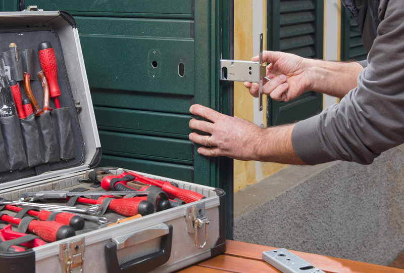 Technicien posant une serrure sur une porte avec mallette d'outils ouverte