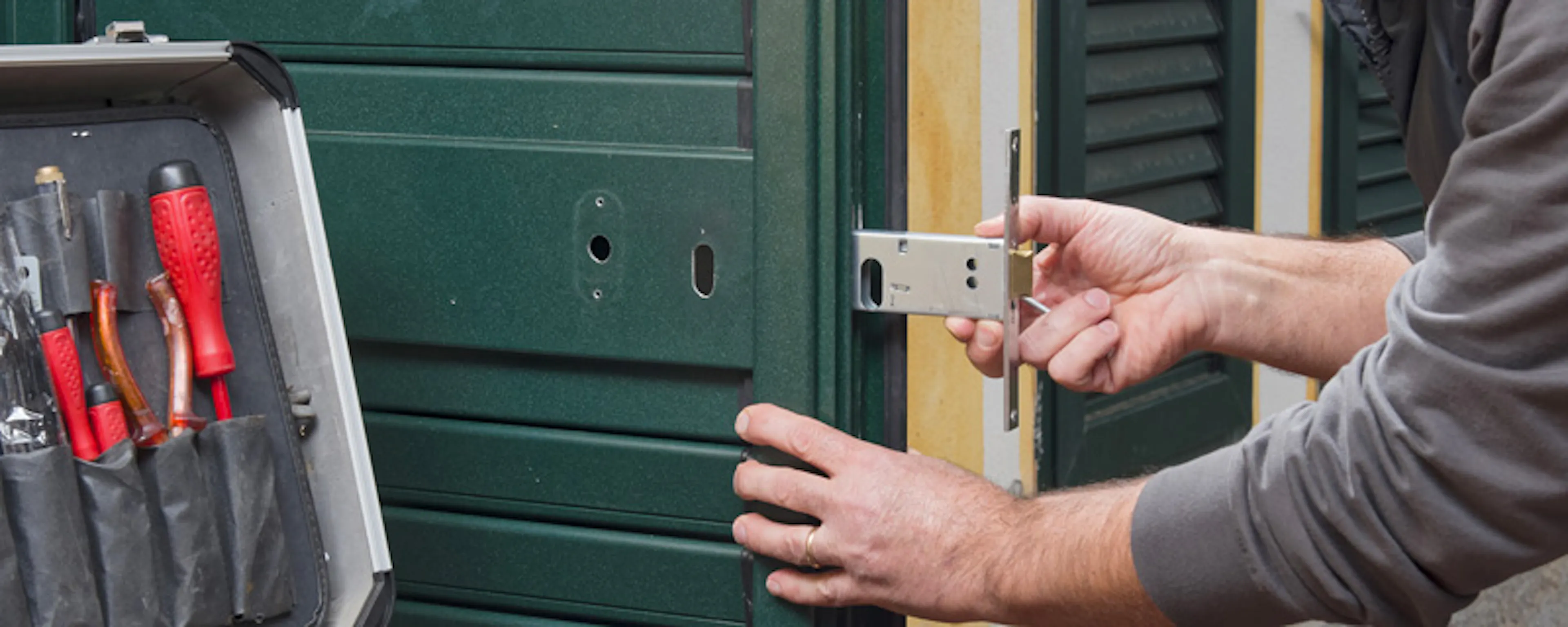 Technicien posant une serrure sur une porte avec mallette d'outils ouverte