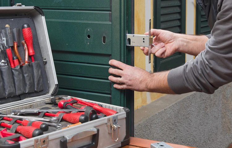Technicien posant une serrure sur une porte avec mallette d'outils ouverte