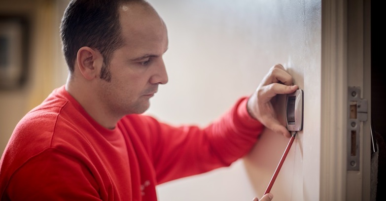 Homme en rouge installant ou vérifiant un interrupteur mural