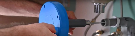 Mains installant un mécanisme de chasse d'eau bleu sur des tuyaux