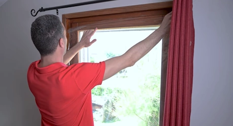 Homme en rouge ajustant un volet ou panneau de fenêtre en bois