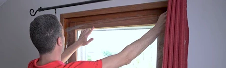 Homme en rouge ajustant un volet ou panneau de fenêtre en bois