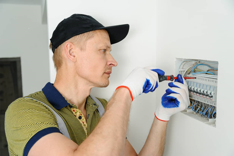 Électricien intervenant sur un tableau électrique mural