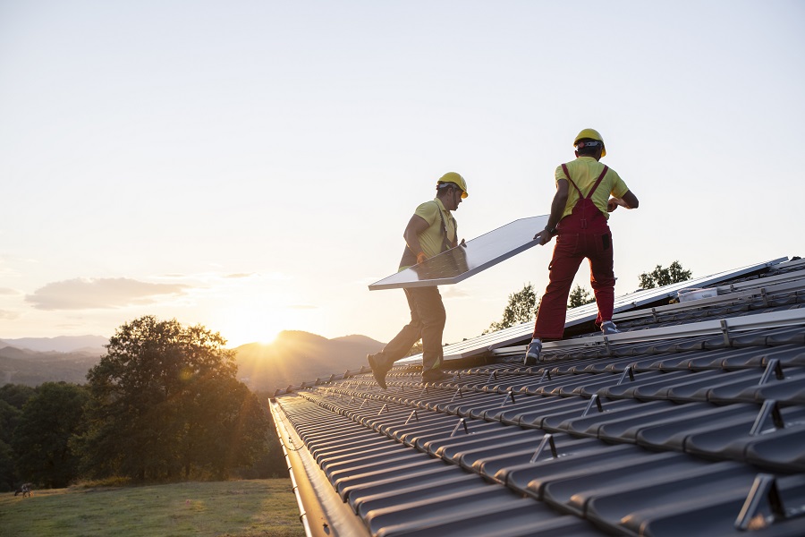 Rangée de panneaux solaires bleus sur toit de maison avec cheminée en briques