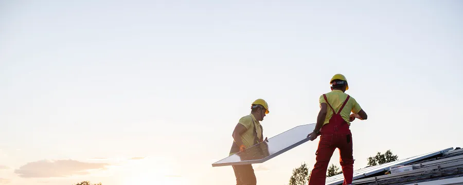 Rangée de panneaux solaires bleus sur toit de maison avec cheminée en briques