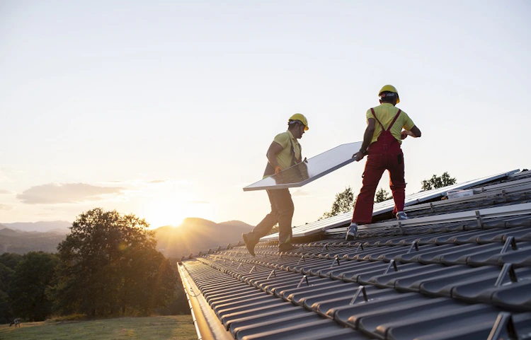 Rangée de panneaux solaires bleus sur toit de maison avec cheminée en briques