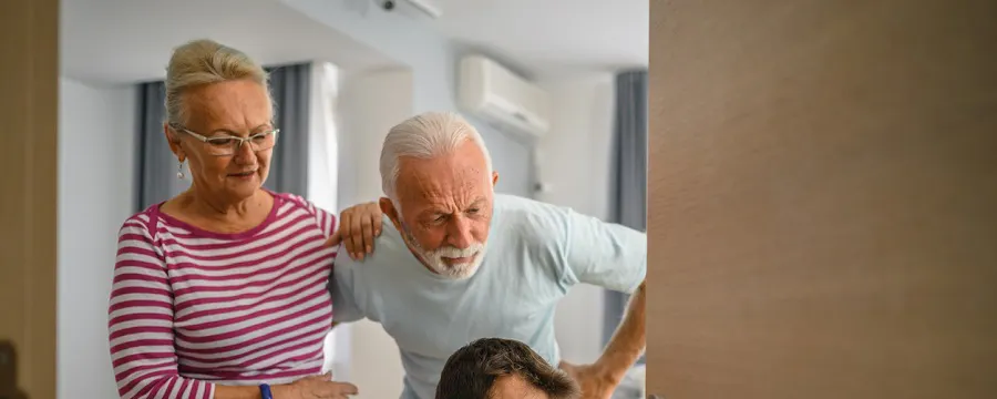 Technicien souriant réparant une porte chez un couple de seniors