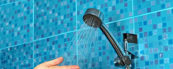 Main sous un pommeau de douche noir avec eau qui coule