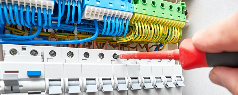 Électricien testant un tableau électrique avec fils multicolores