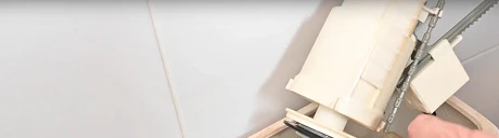 Main montrant l'intérieur rouillé d'un réservoir de toilettes ouvert