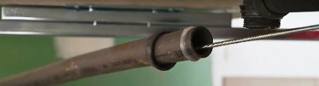 Tuyau métallique corrodé sous un meuble avec traces d'humidité