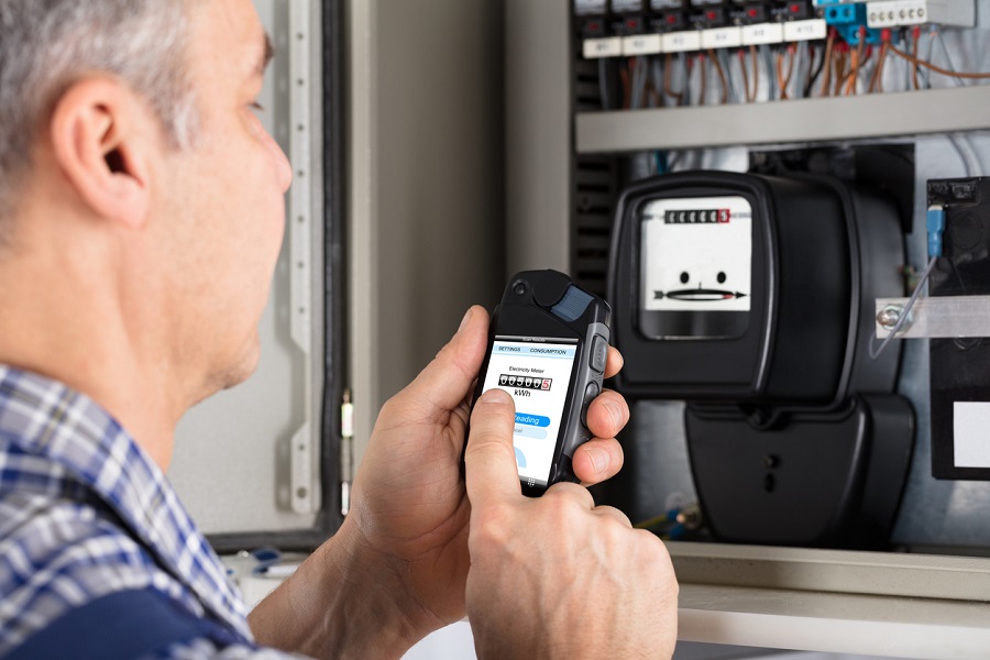Homme photographiant un compteur électrique avec son smartphone