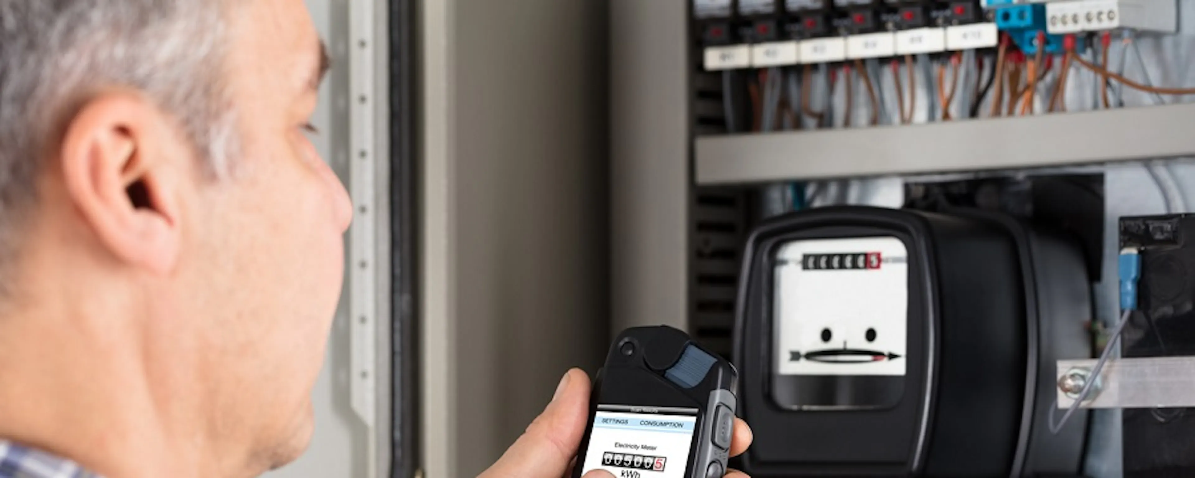 Homme photographiant un compteur électrique avec son smartphone