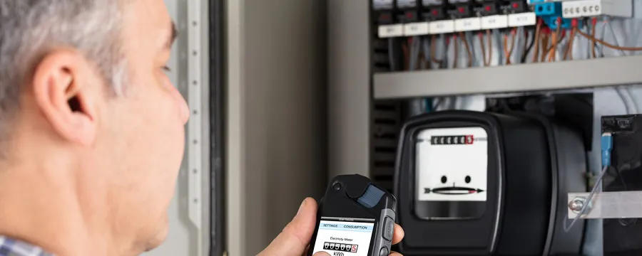 Homme photographiant un compteur électrique avec son smartphone