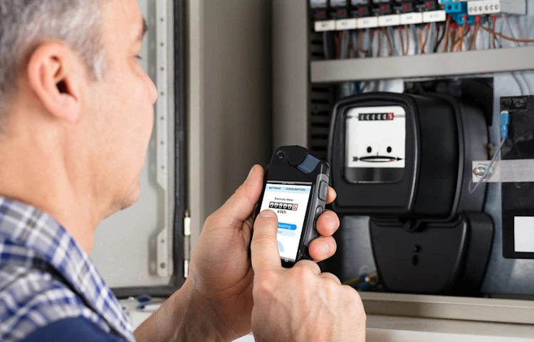 Homme photographiant un compteur électrique avec son smartphone